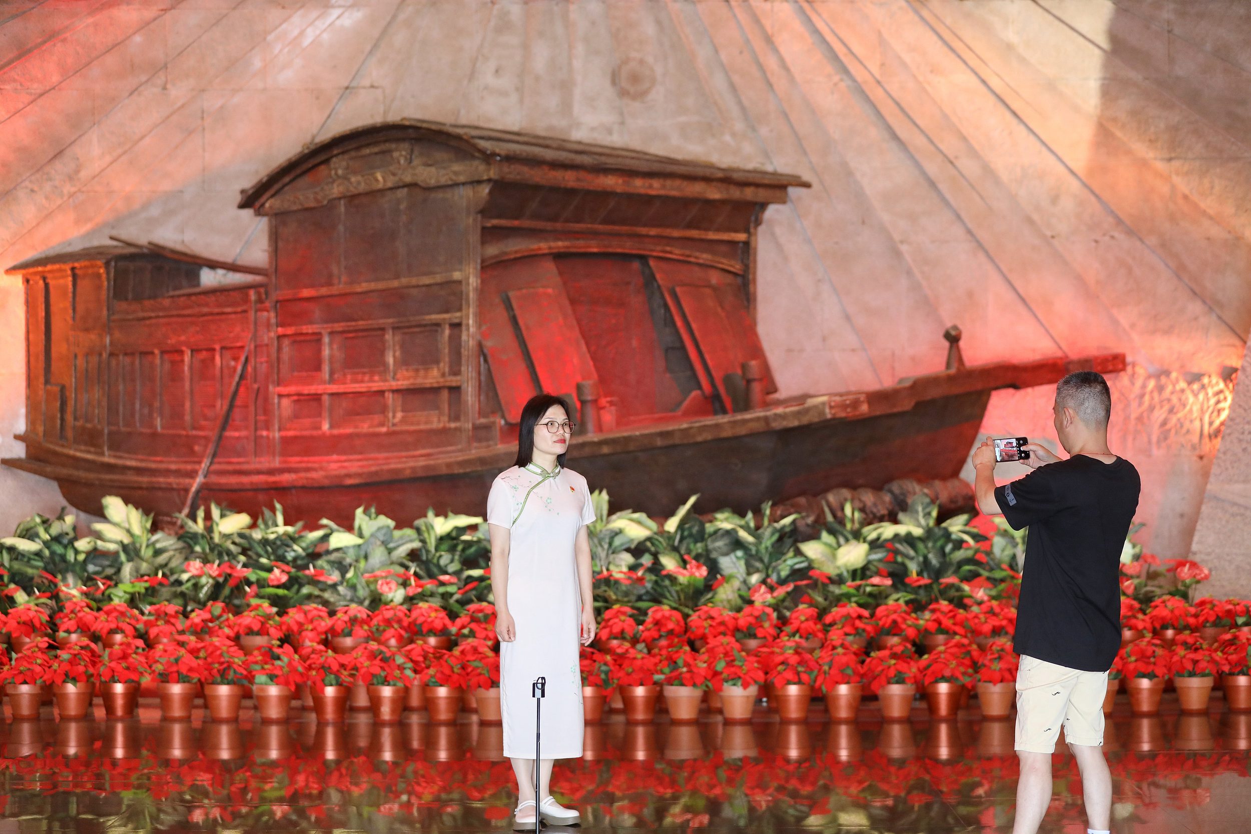 2025年6月24日，浙江嘉興，游客在南湖革命紀(jì)念館與紅船雕塑合影。（圖片來源：視覺中國）